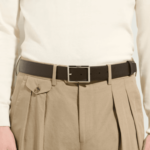 Cintura Montblanc Sartorial in pelle goffrata marrone con fibbia rettangolare in palladio lucido, indossata su pantaloni beige con tasca a pattina.