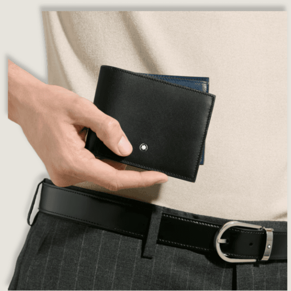 Portafoglio Montblanc nero in mano, abbinato a cintura elegante e abbigliamento sartoriale.